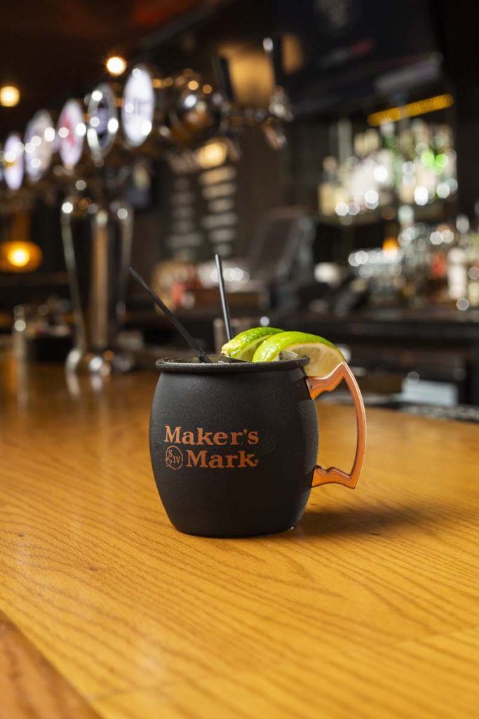 Frosty mule beverage in black Matt the Miller’s mule mug with copper handle sitting on oak bar