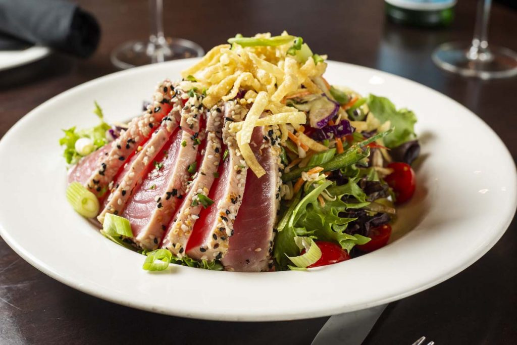 Seared rare Ahi tuna, sliced and arranged on bed of greens