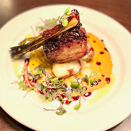 Crispy Pork Belly served on Butternut Squash Bisque, with Roasted Red Potatoes, Smoked Berry Glaze, and Charred Leek