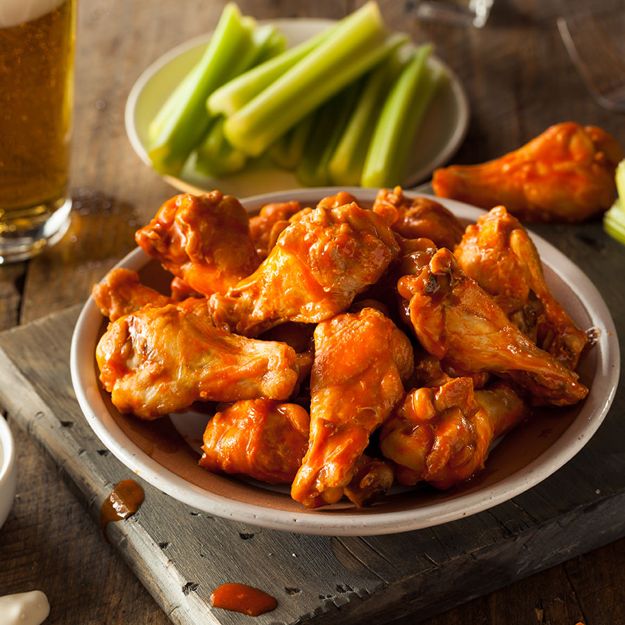 Bowl of wings with celery sticks and glass of draft beer